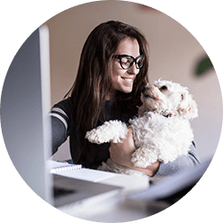 Woman working on computer smiling at dog